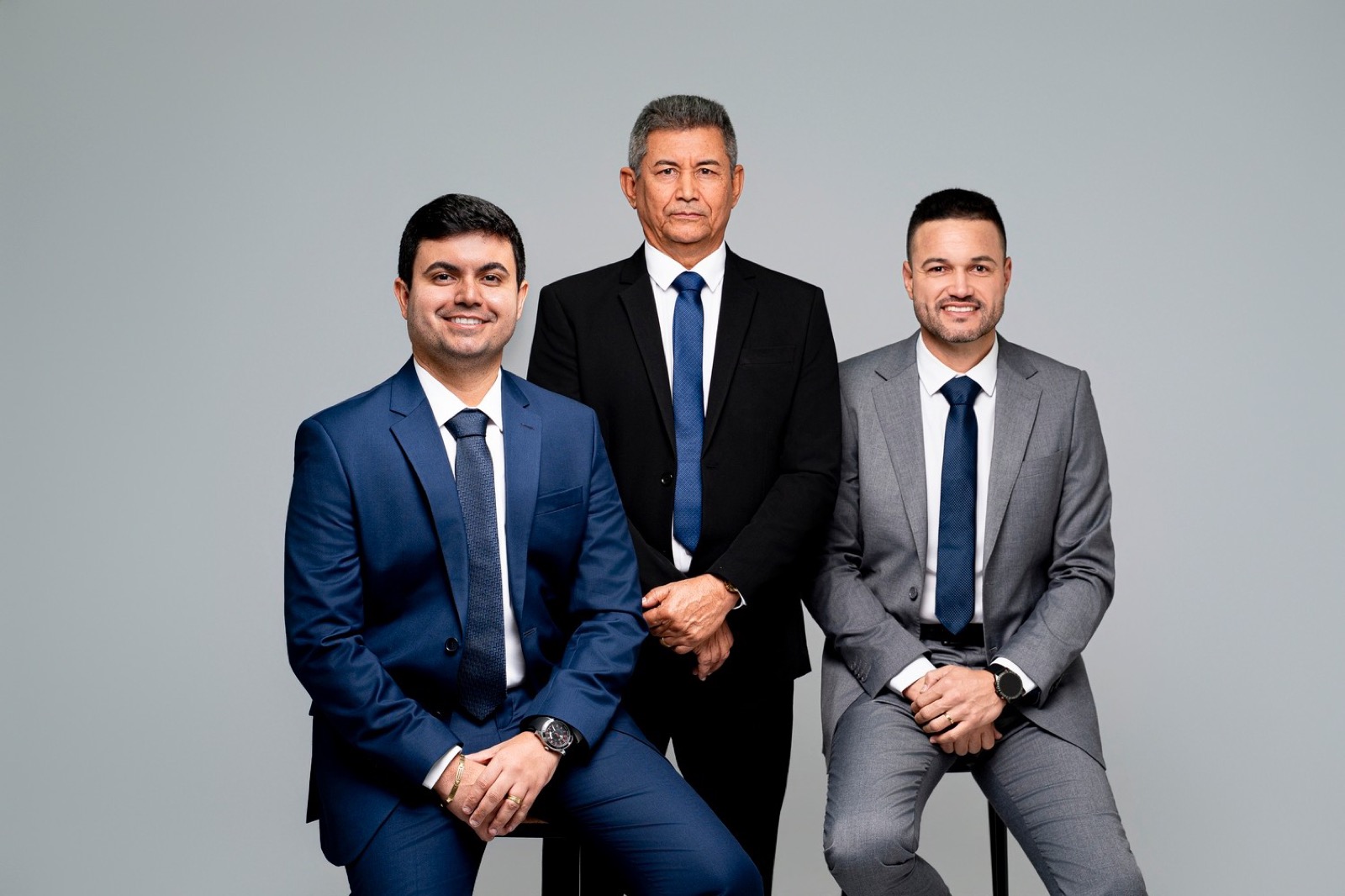 Os três sócios sorrindo, em retrato de estúdio